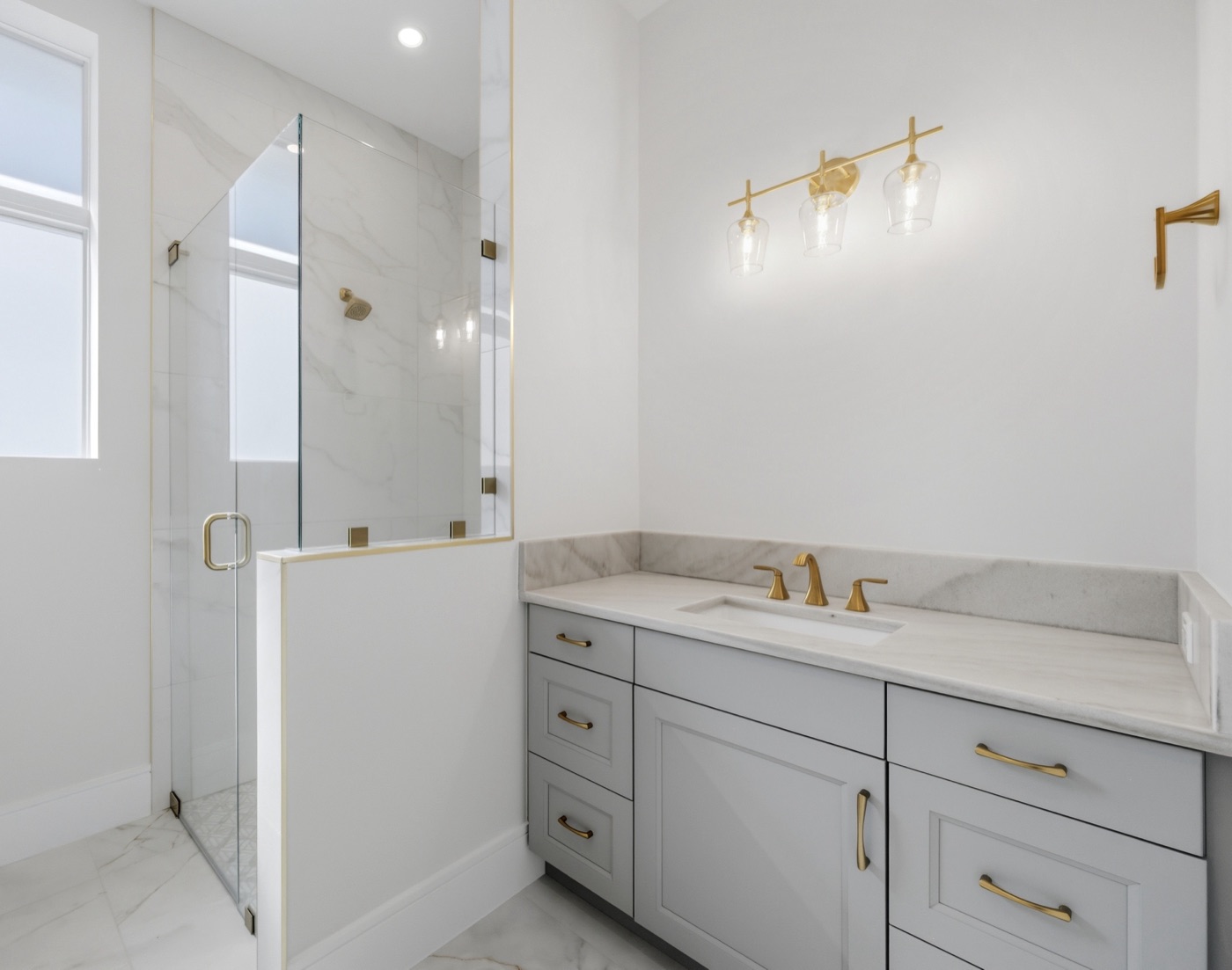 Guest bath with marble-look shower, dove-gray vanity and amber-glass vanity light — Coastal Residence