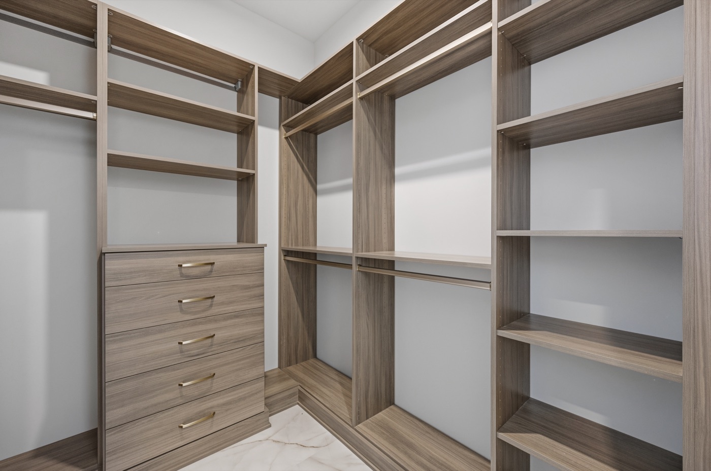 Custom walk-in closet in driftwood wood-grain with brushed-brass pulls — Coastal Residence